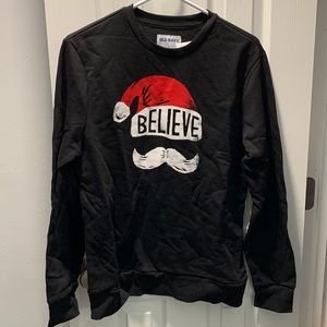 Black sweatshirt with Santa hat and “believe” saying.